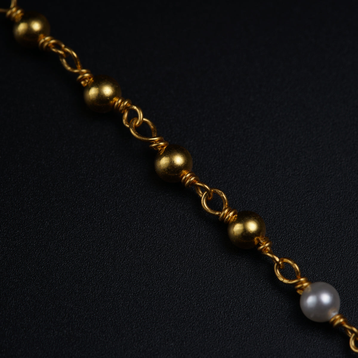 a close up of a gold chain with pearls