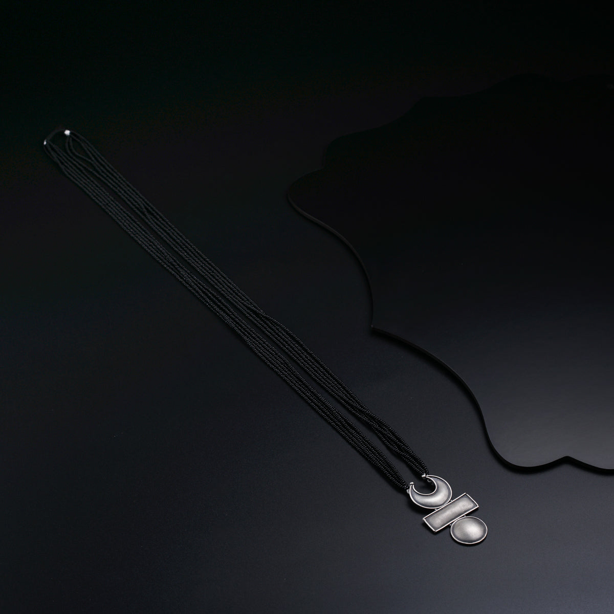 a necklace with a black cord and a white bead