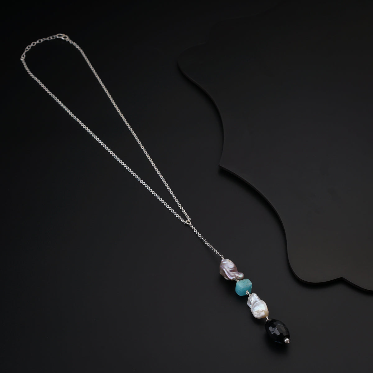 a necklace with three beads on a black background