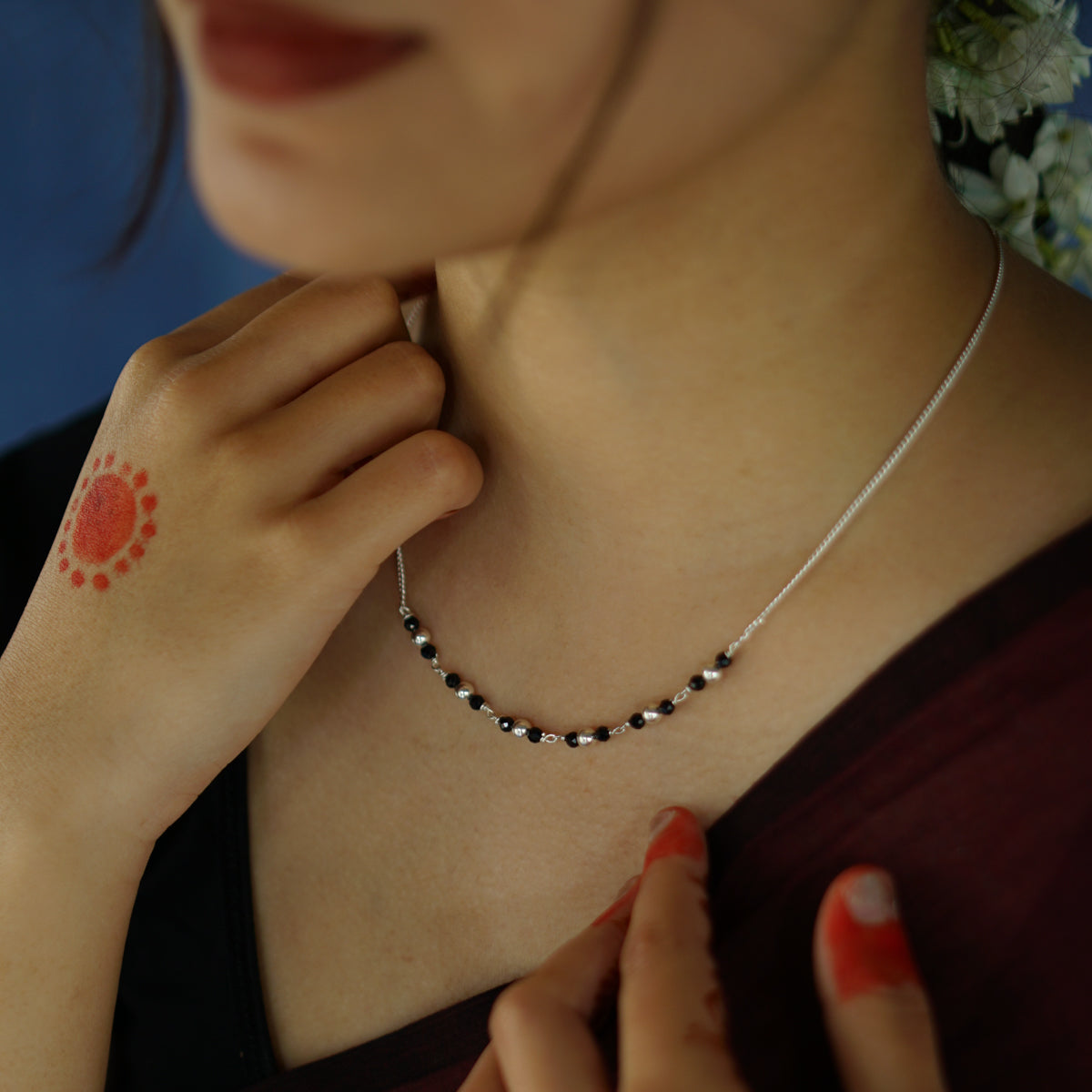 a woman wearing a necklace with a flower on it
