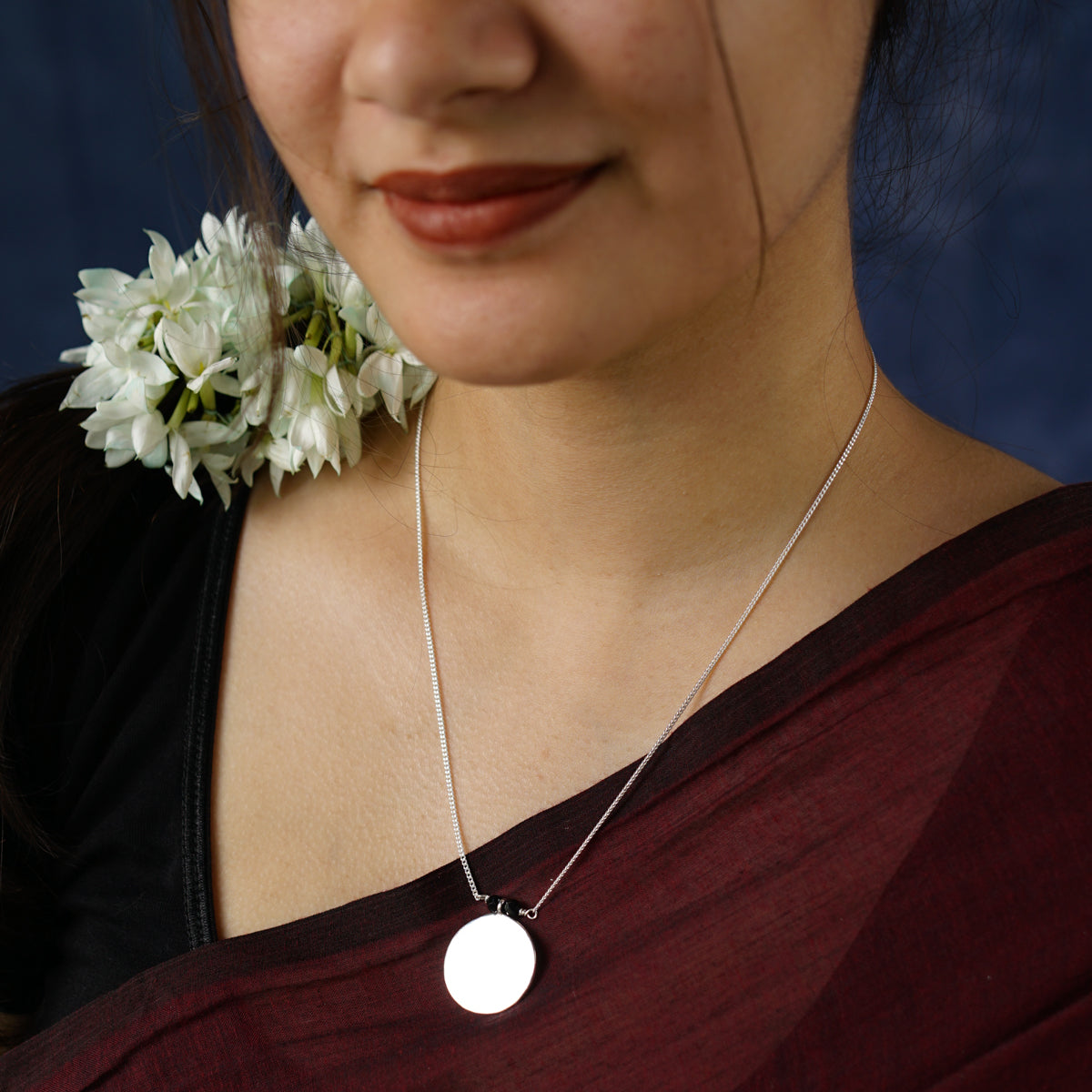 a woman wearing a necklace with a flower on it