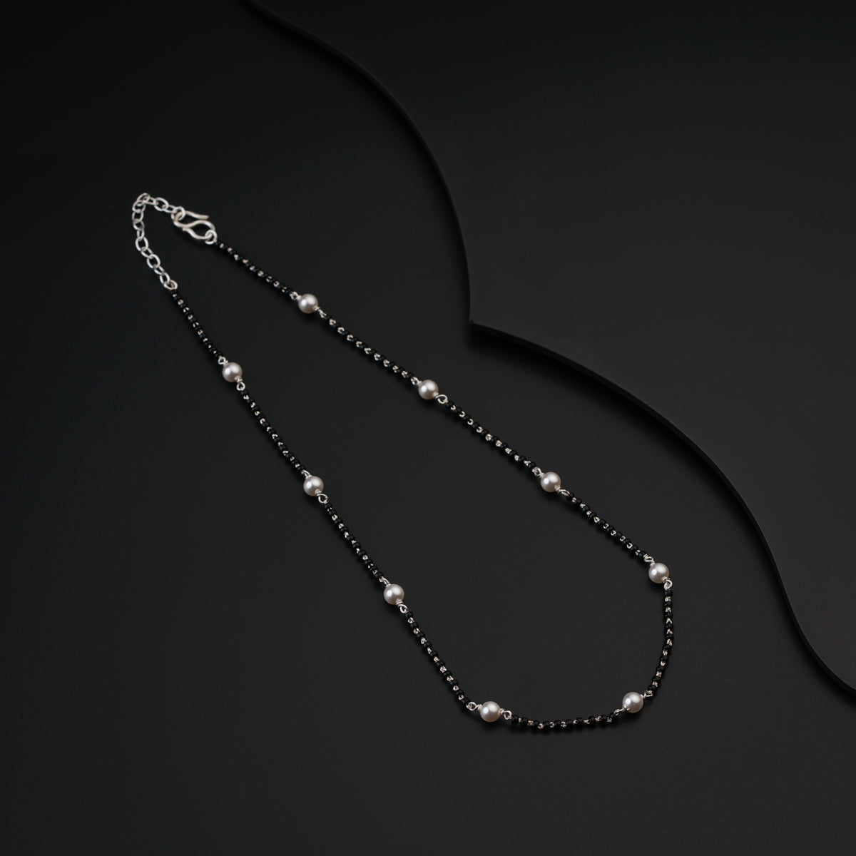 a black beaded necklace on a black surface