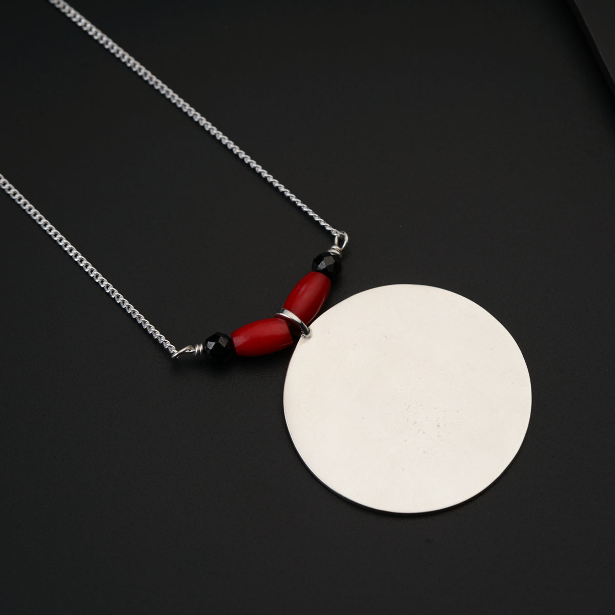 a white disc with a red handle on a chain