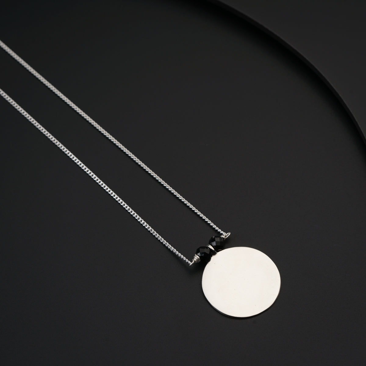 a necklace with a disc on a black background