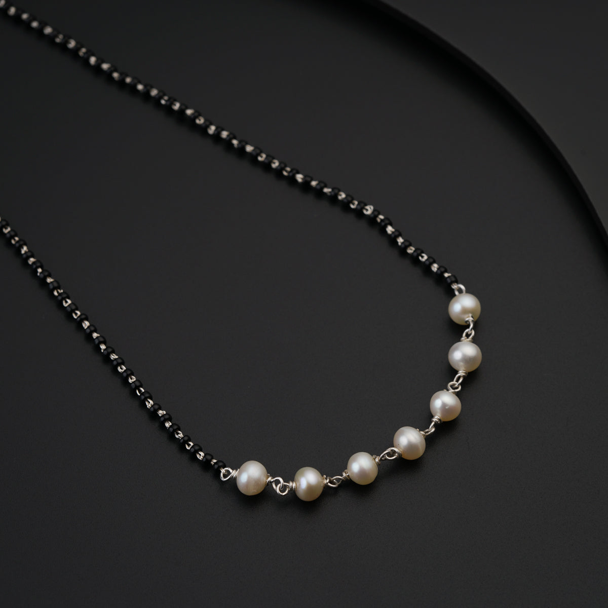 a necklace with pearls on a black surface
