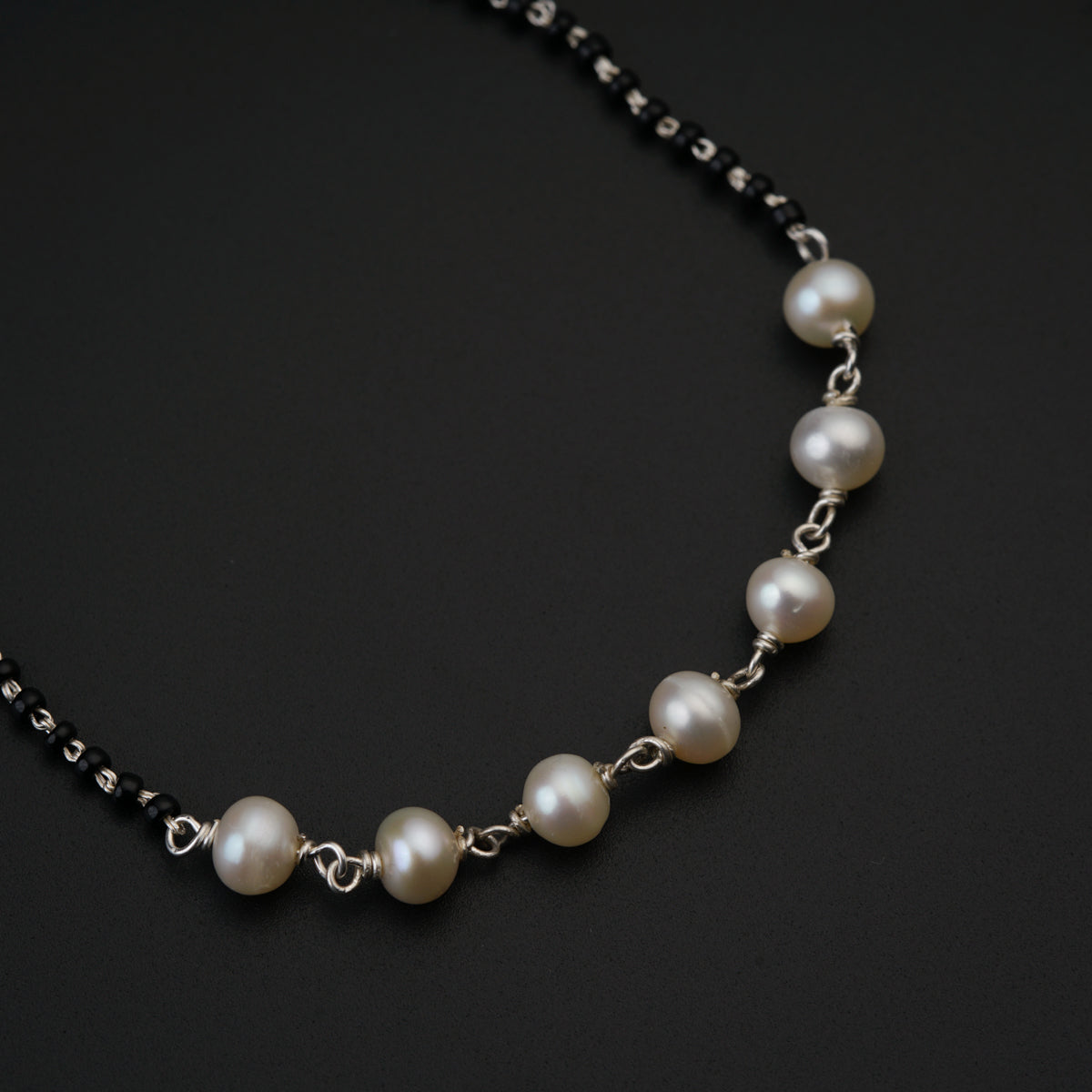 a necklace with pearls on a black background