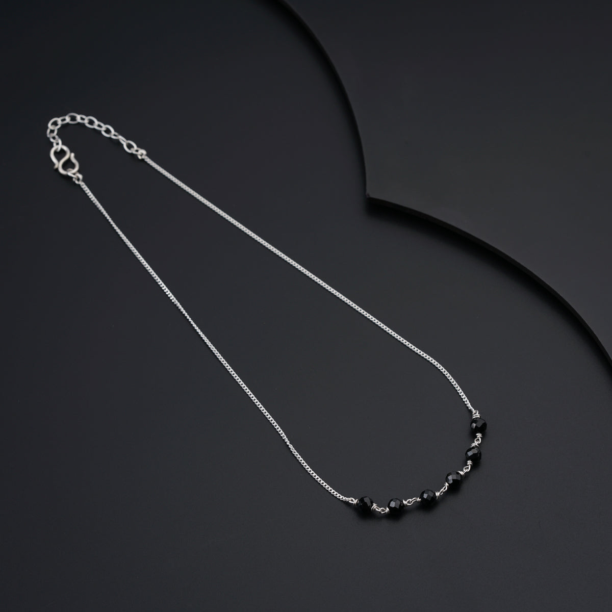 a black and white necklace on a black surface