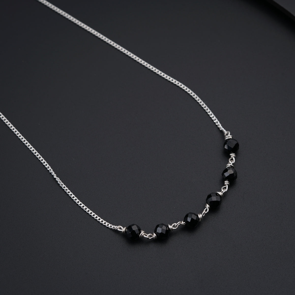 a black beaded necklace on a black surface