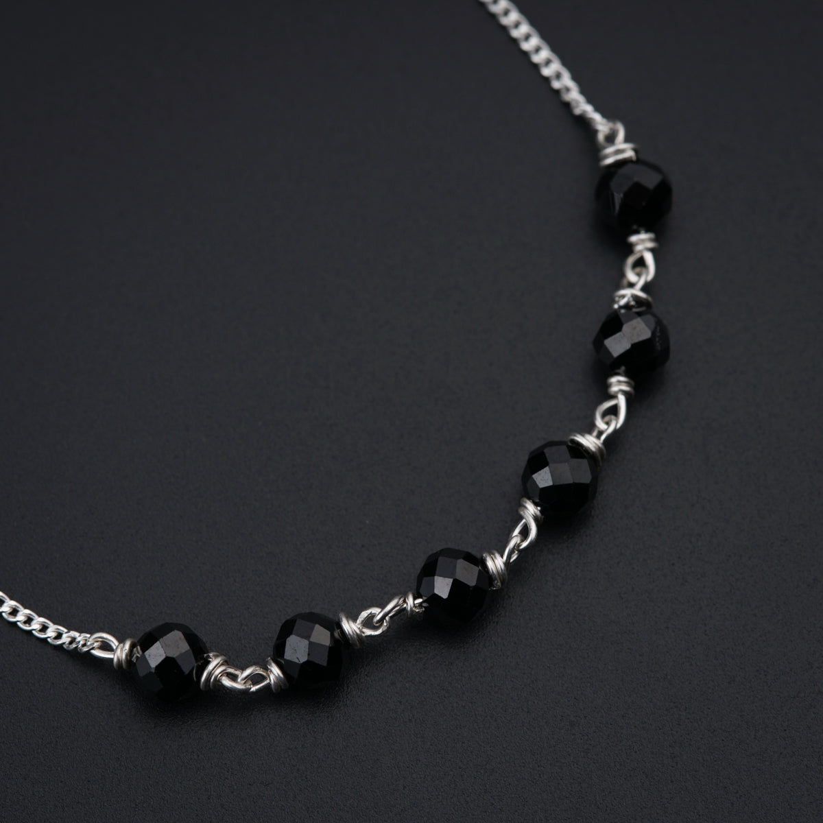 a black and silver necklace on a black surface