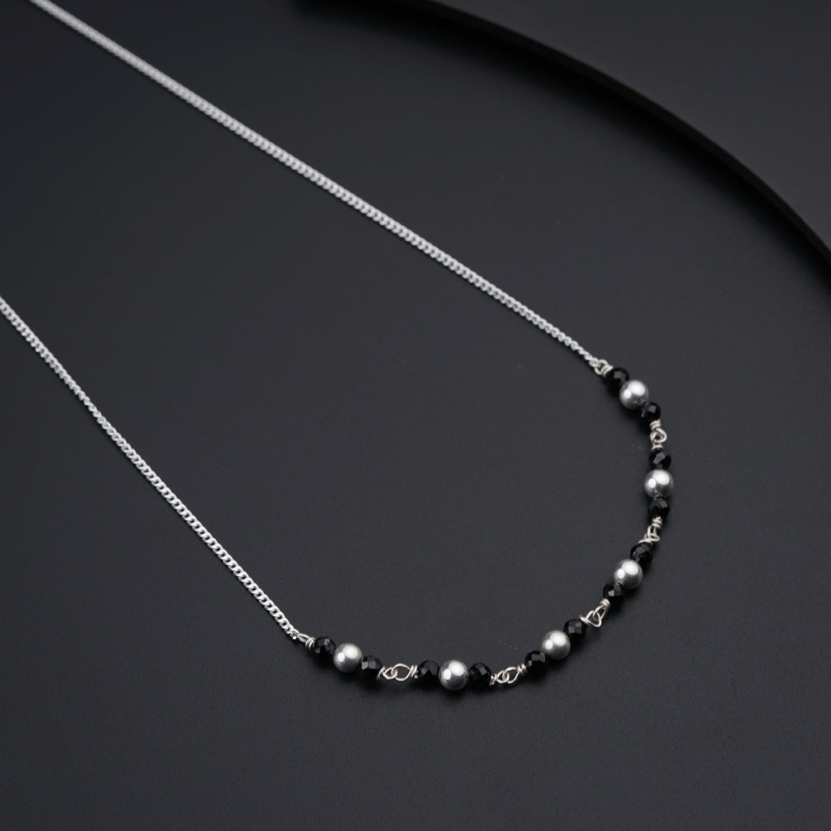 a black and silver beaded necklace on a black surface