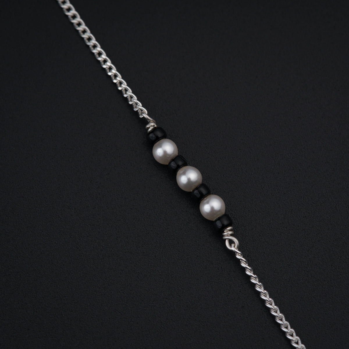 a necklace with three pearls on a chain