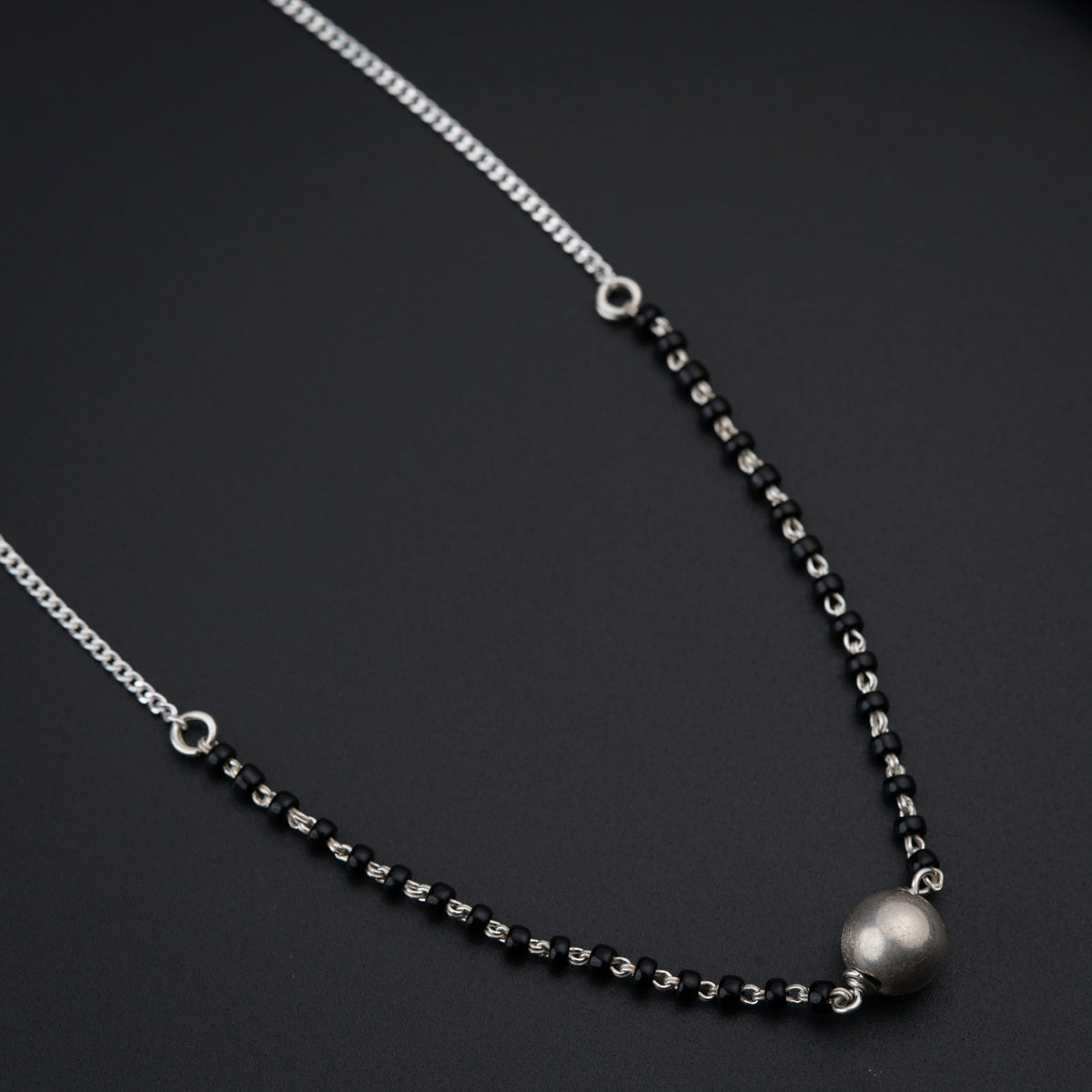a black and silver necklace on a black surface