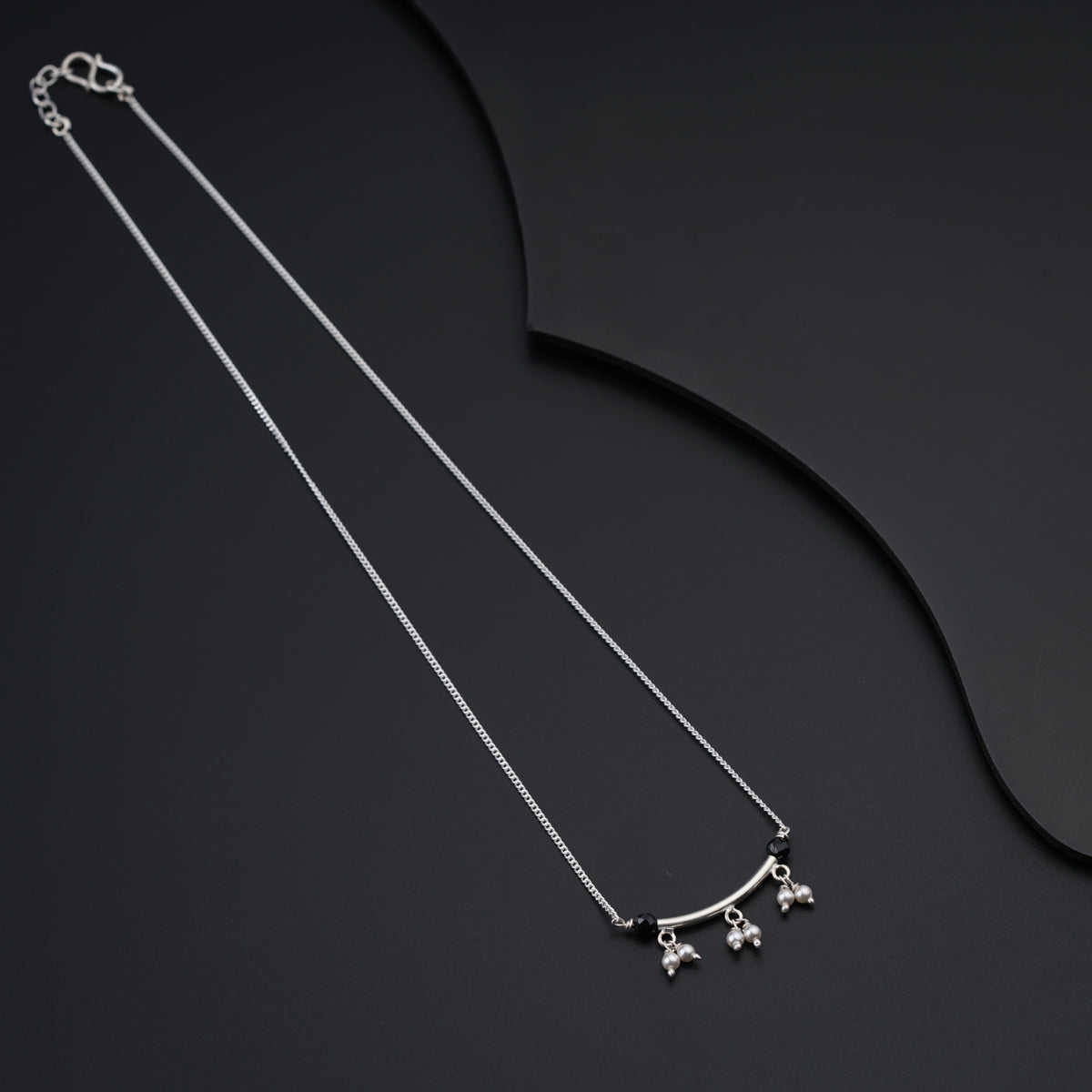 a pair of silver necklaces on a black surface