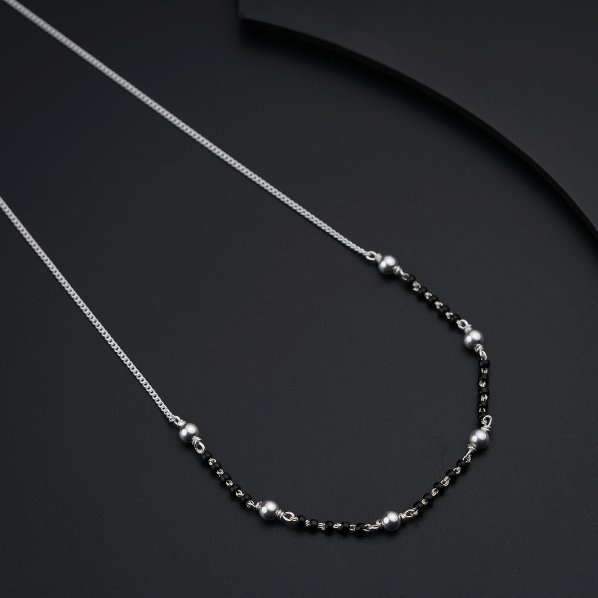 a black and silver necklace on a black surface
