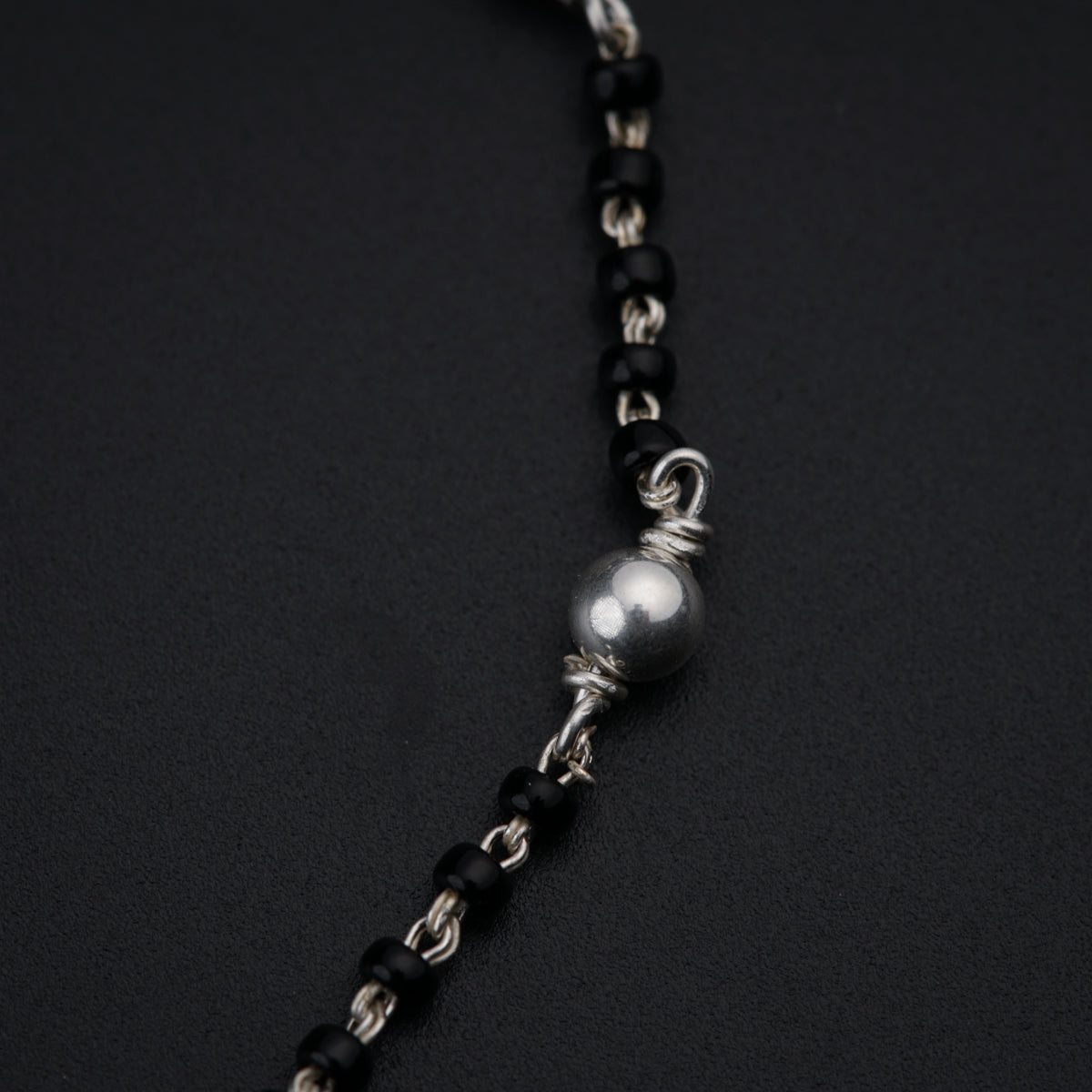 a black and silver beaded necklace on a black surface