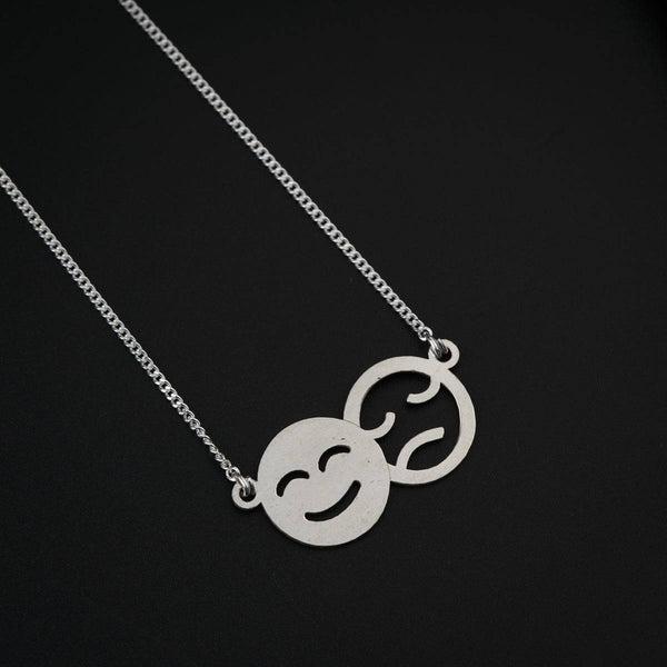 Close-up of silver smiley and sad face pendant necklace