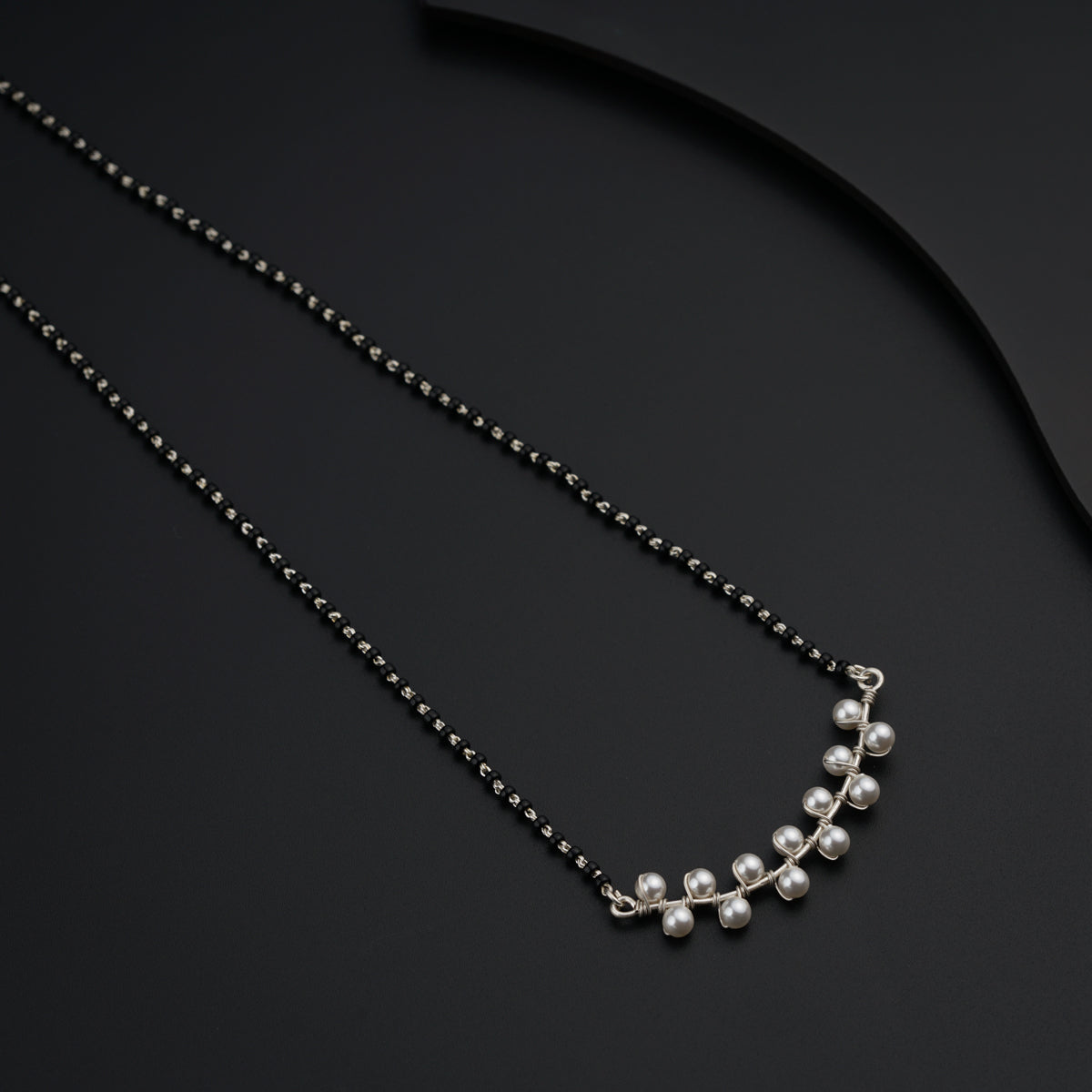 a necklace with pearls on a black surface