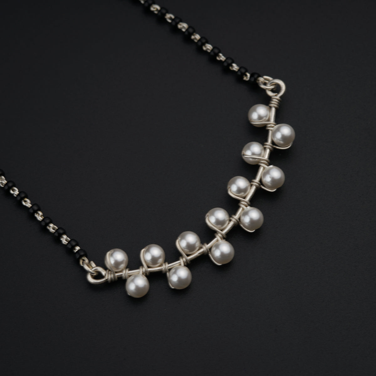a necklace with pearls on a black background