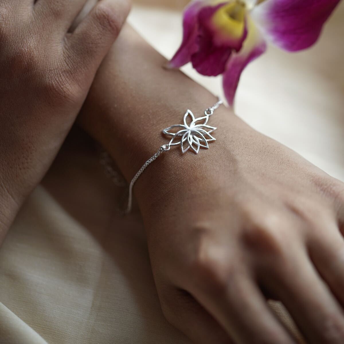 Silver lotus bracelet on wrist with orchid flower