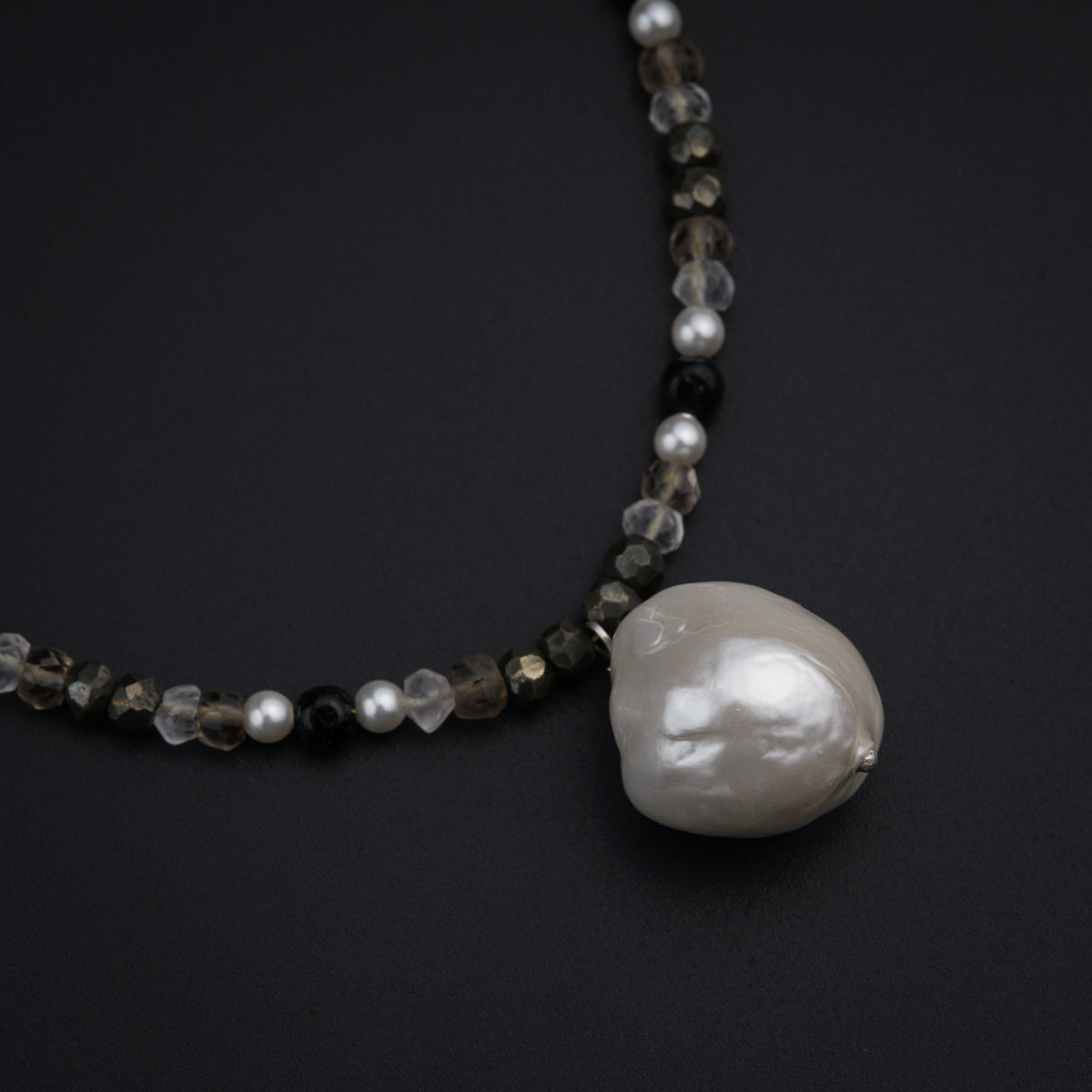 a necklace with a white pearl and black beads