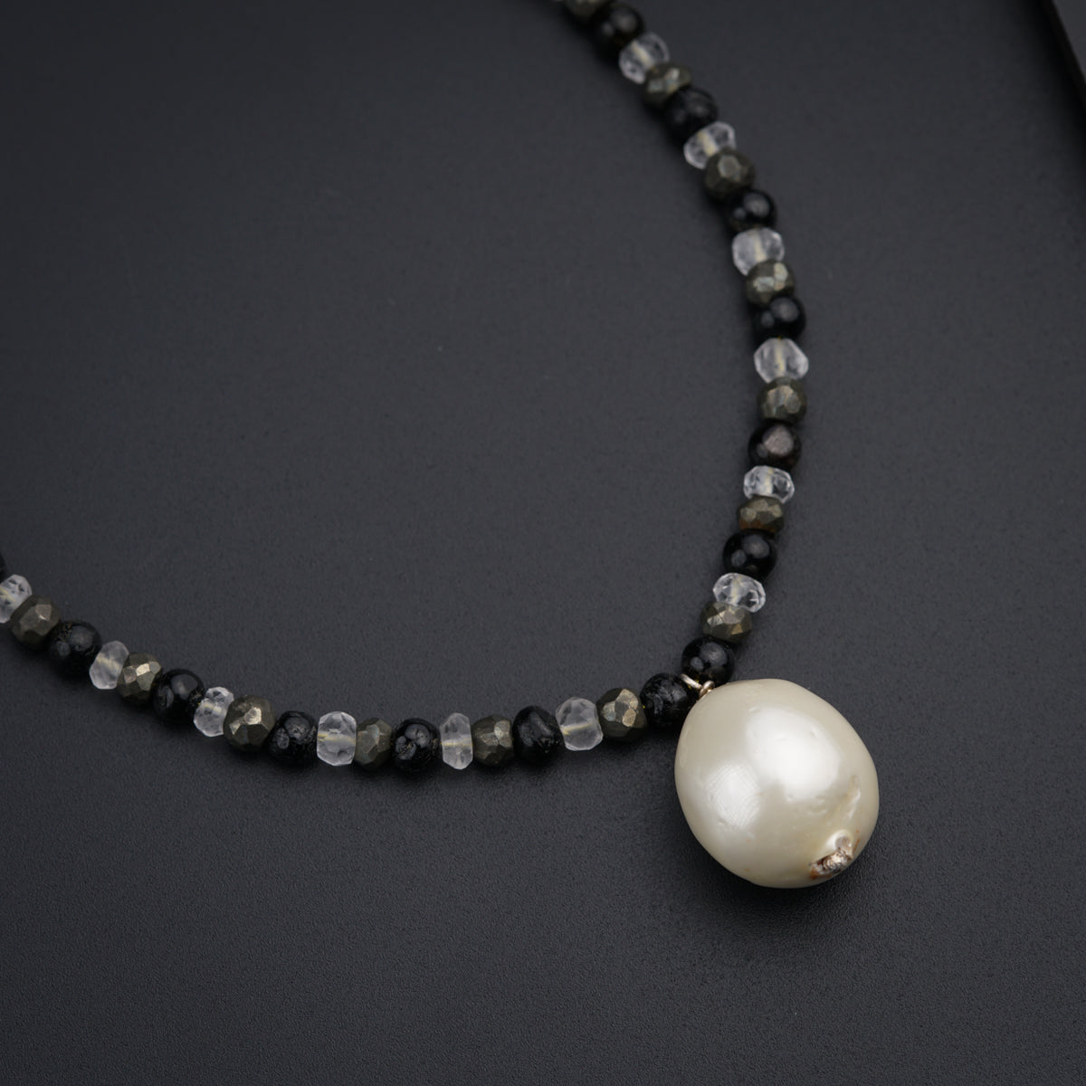 a necklace with a pearl on a black surface