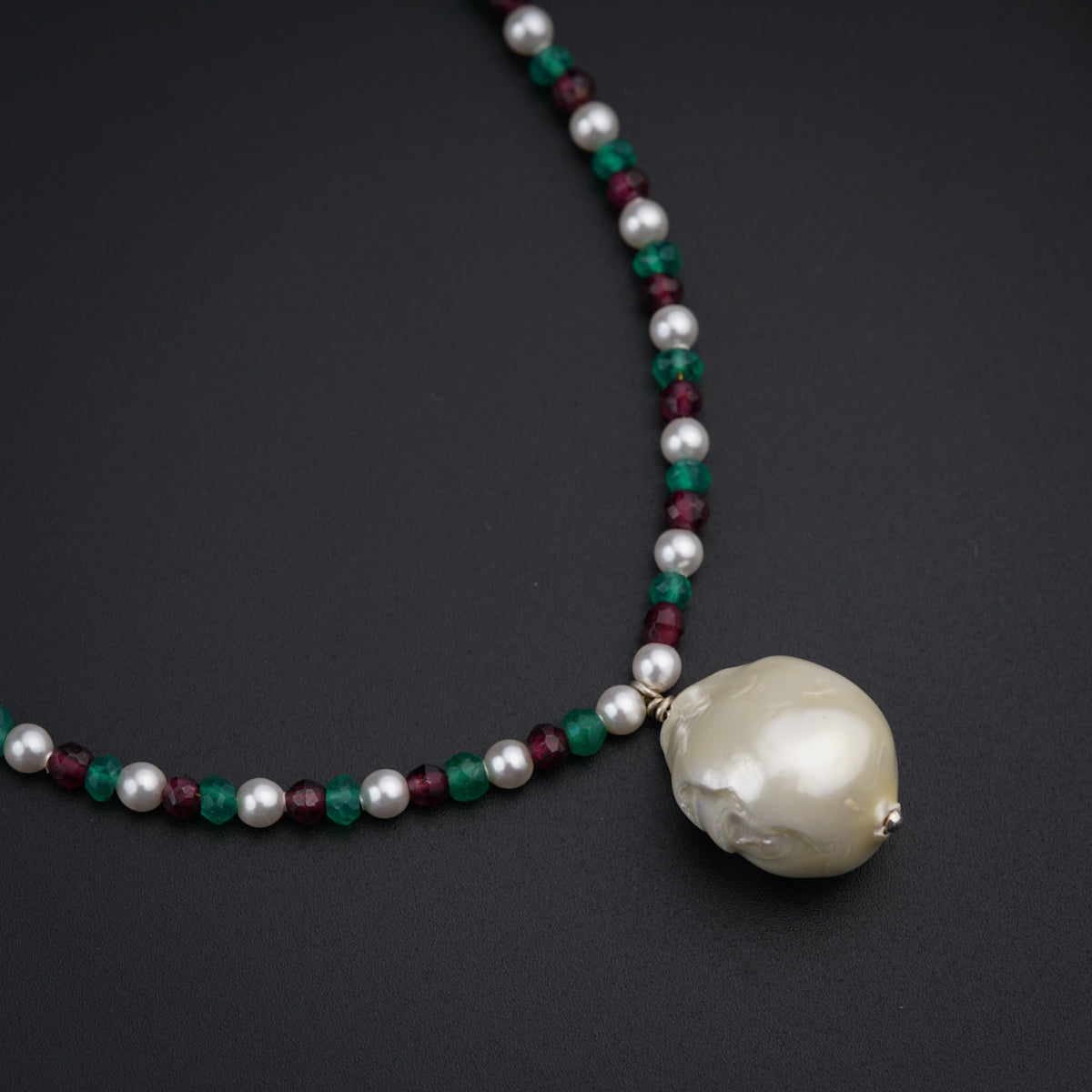 a necklace with a white pearl and green beads