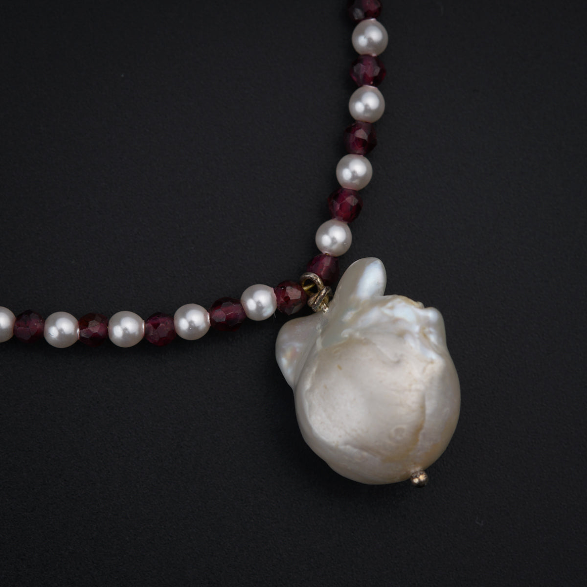 a necklace with a white shell on a beaded necklace