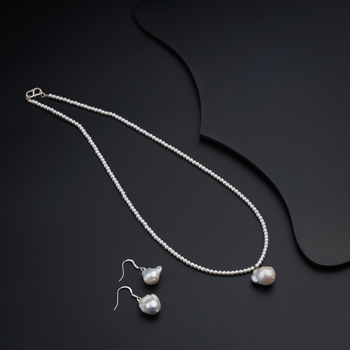 a necklace and earrings on a black surface