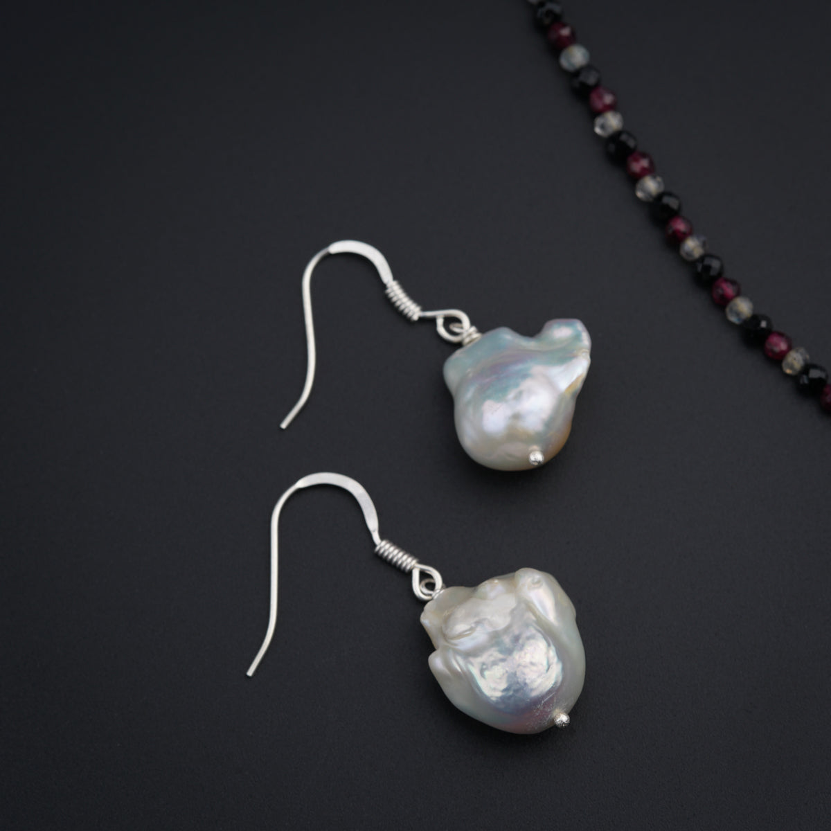 a pair of earrings with pearls on a black surface