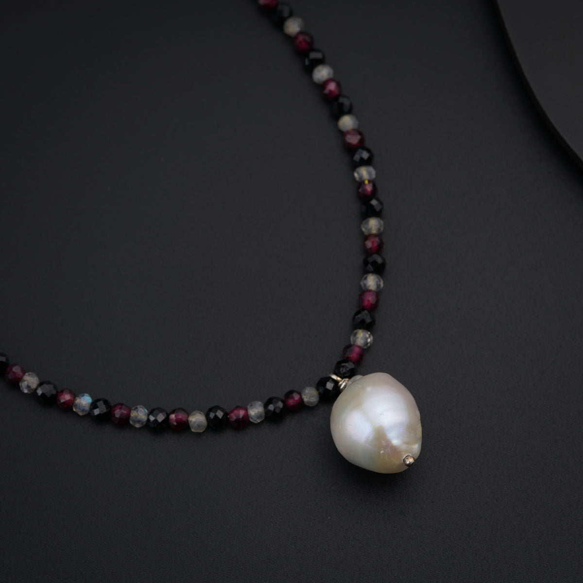 a necklace with a pearl on a black surface