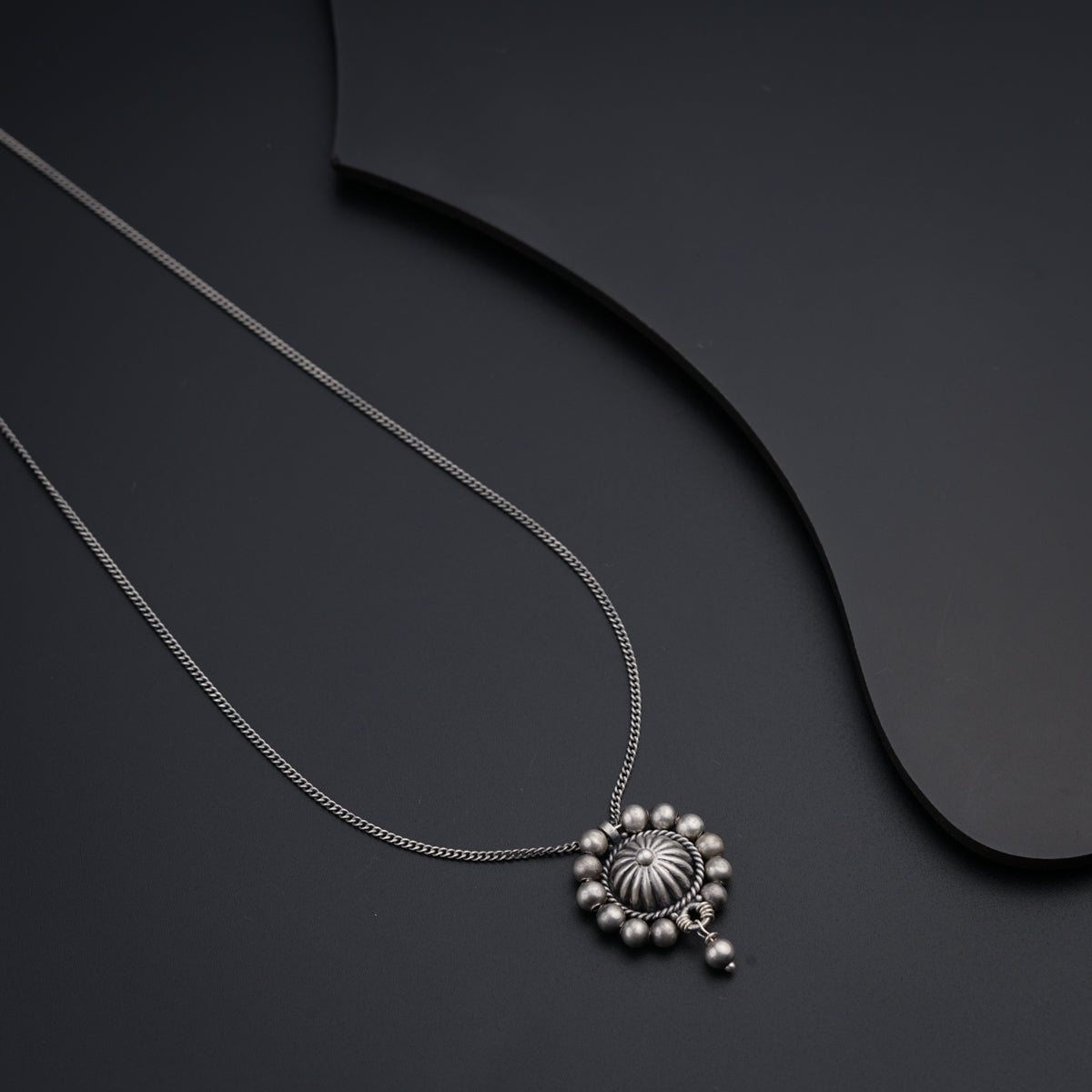 a silver necklace on a black surface