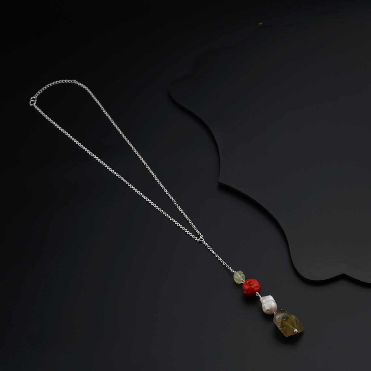 a necklace with three stones on a black background