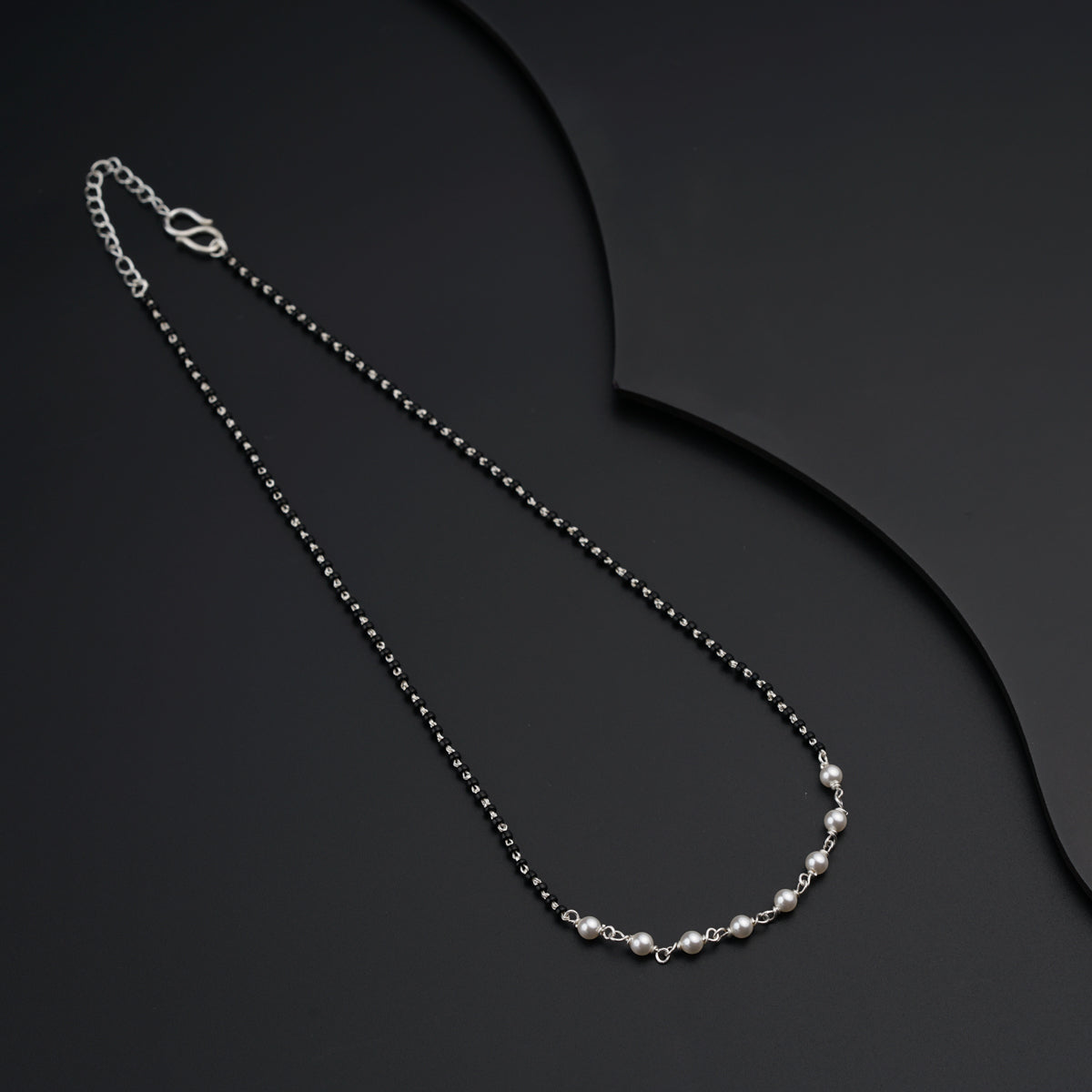 a black and white necklace on a black surface