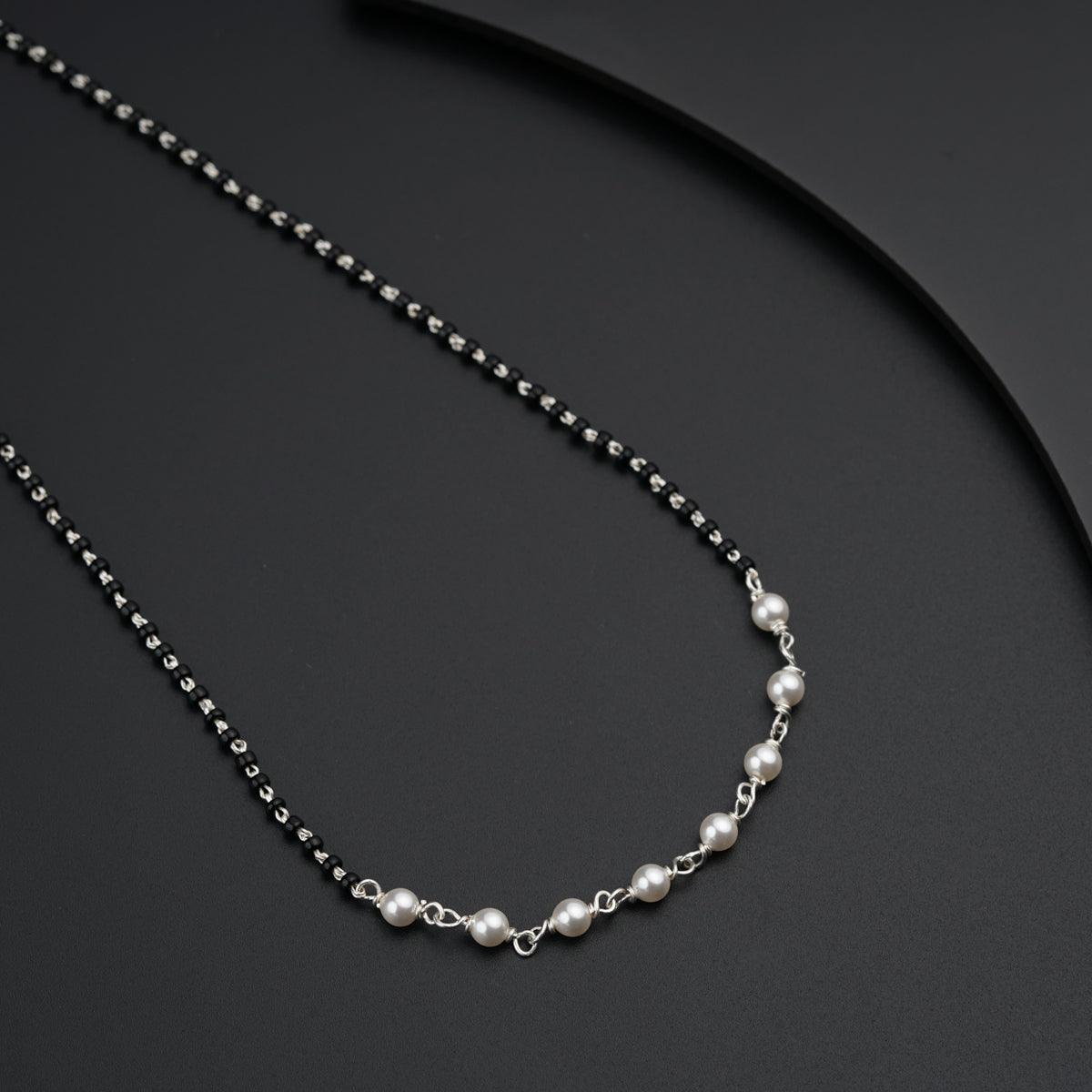 a necklace with pearls on a black surface