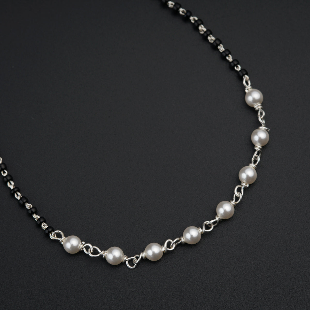 a necklace with pearls on a black background