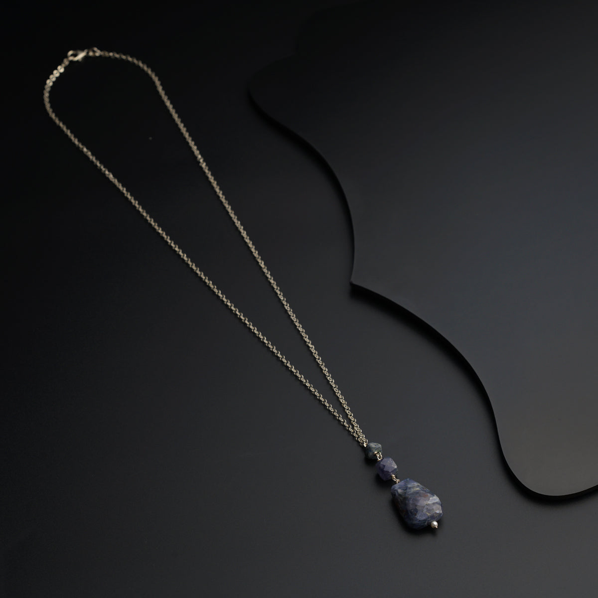 a necklace with a stone on a black background