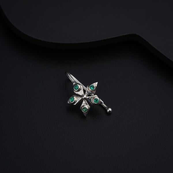 a silver brooch with green stones on a black background