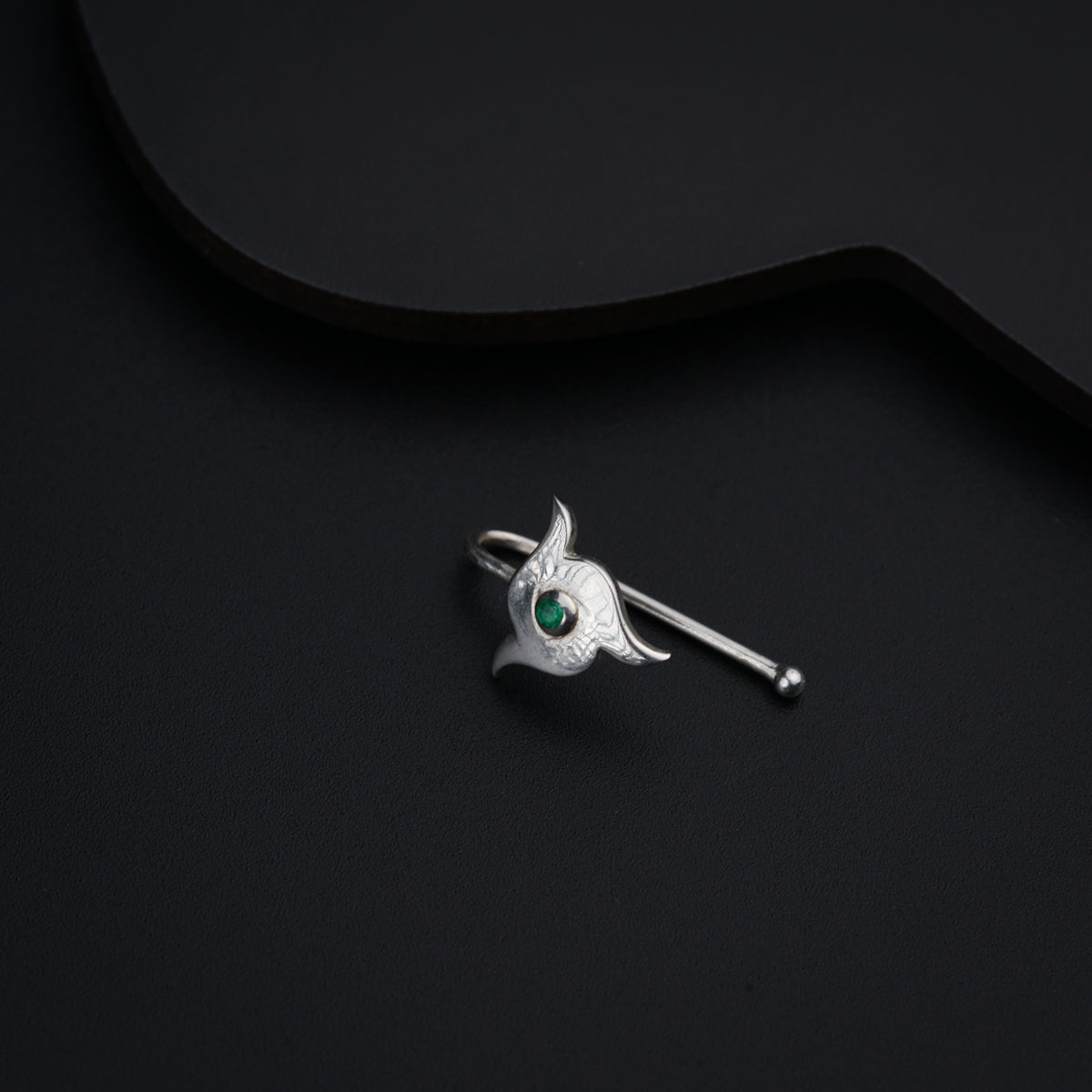a silver brooch with a green eye on it