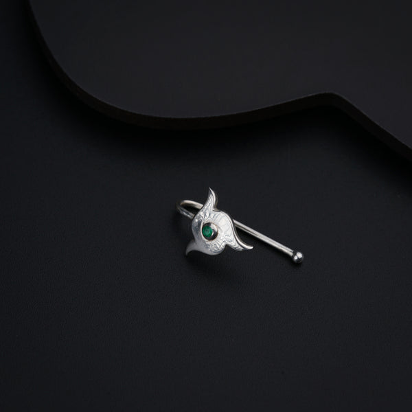a silver brooch with a green eye on it