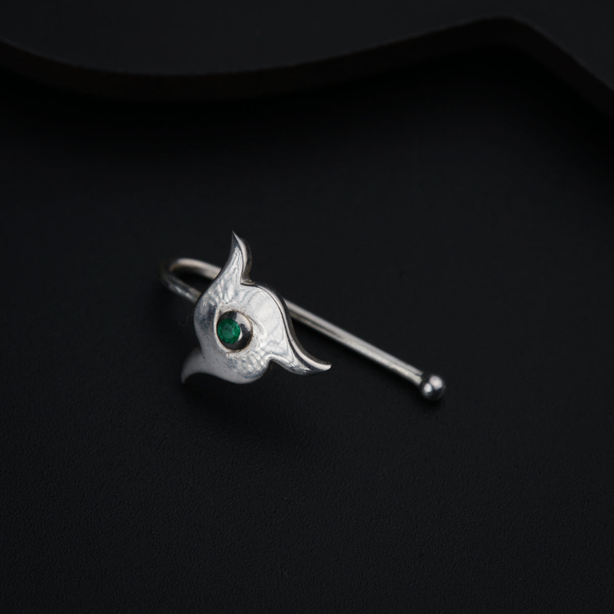 a cat brooch with a green eye on a black background