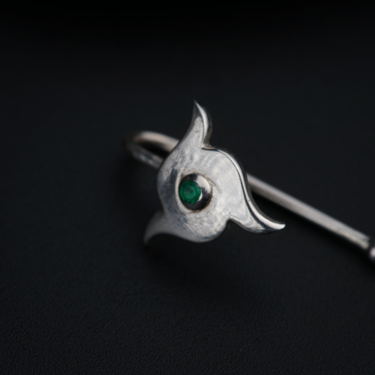 a close up of a ring with a green stone