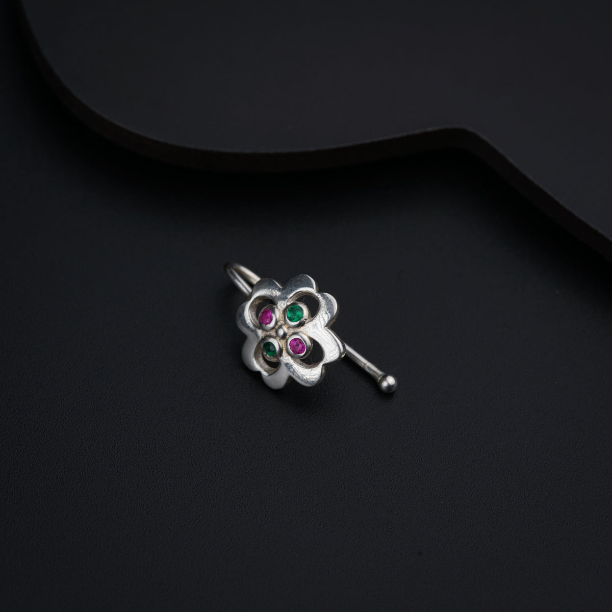 a silver brooch with three stones on a black background