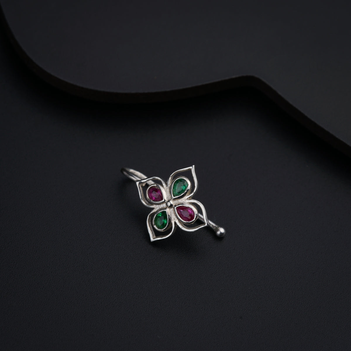 a silver brooch with three stones on a black background