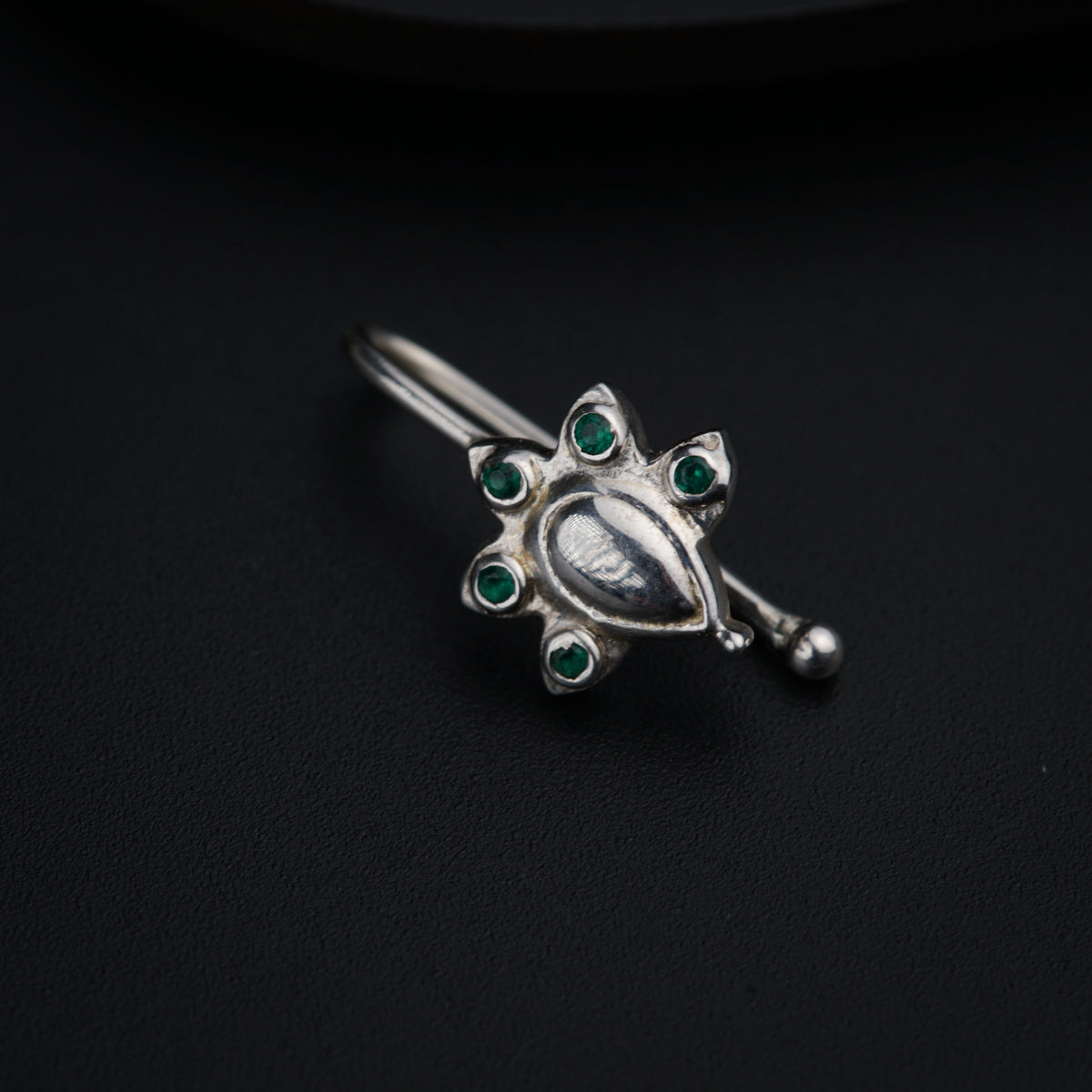 a close up of a brooch on a black surface