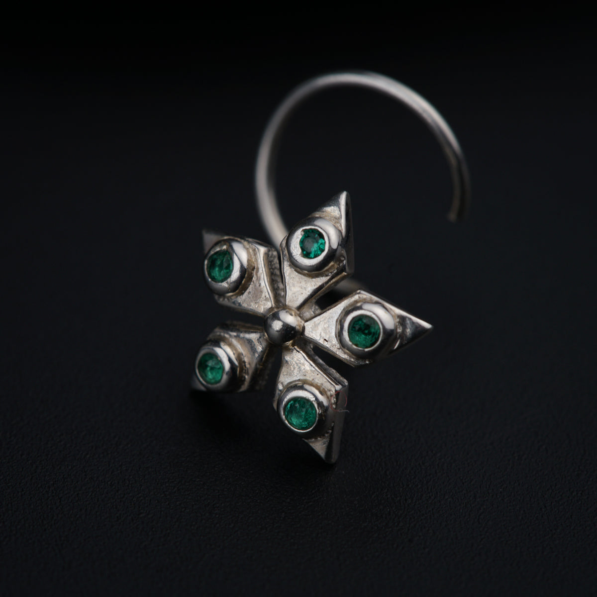 a close up of a silver ring with green stones