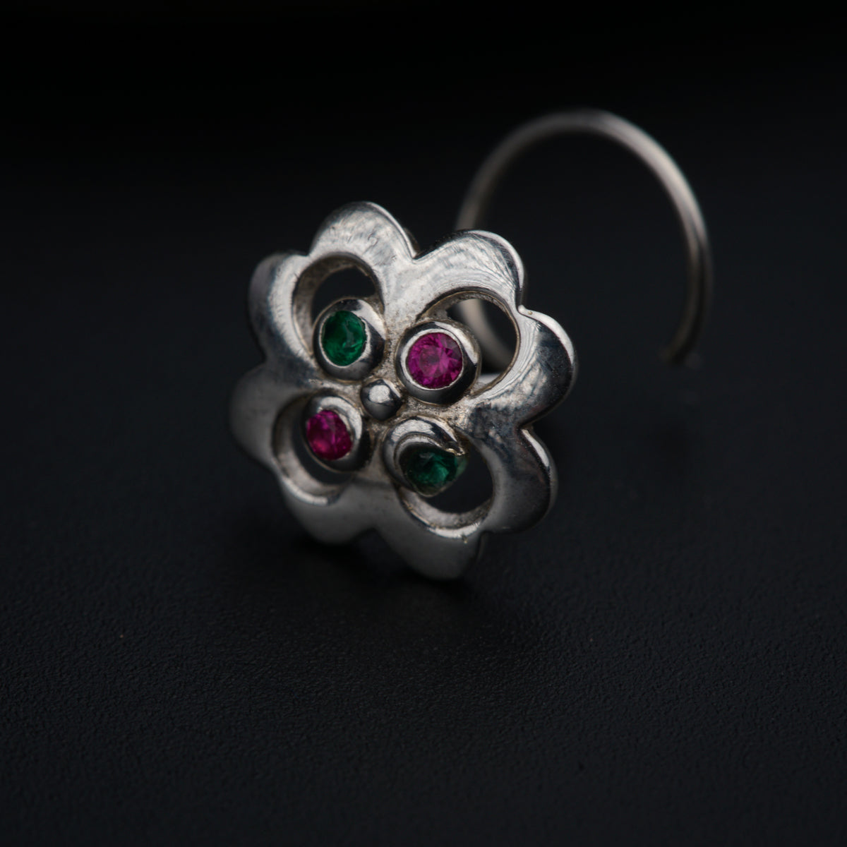 a close up of a flower shaped ring on a black surface