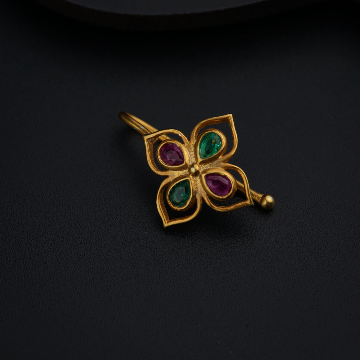 a close up of a brooch on a black surface