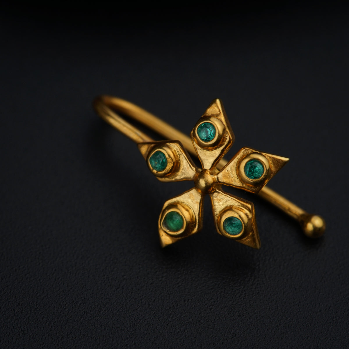 a close up of a gold ring with green stones