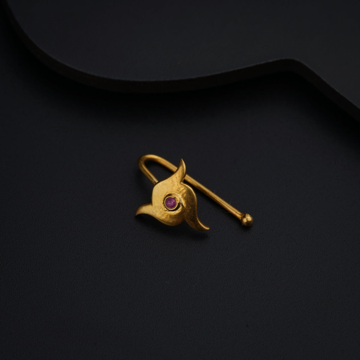 a gold brooch with a pink stone in the center