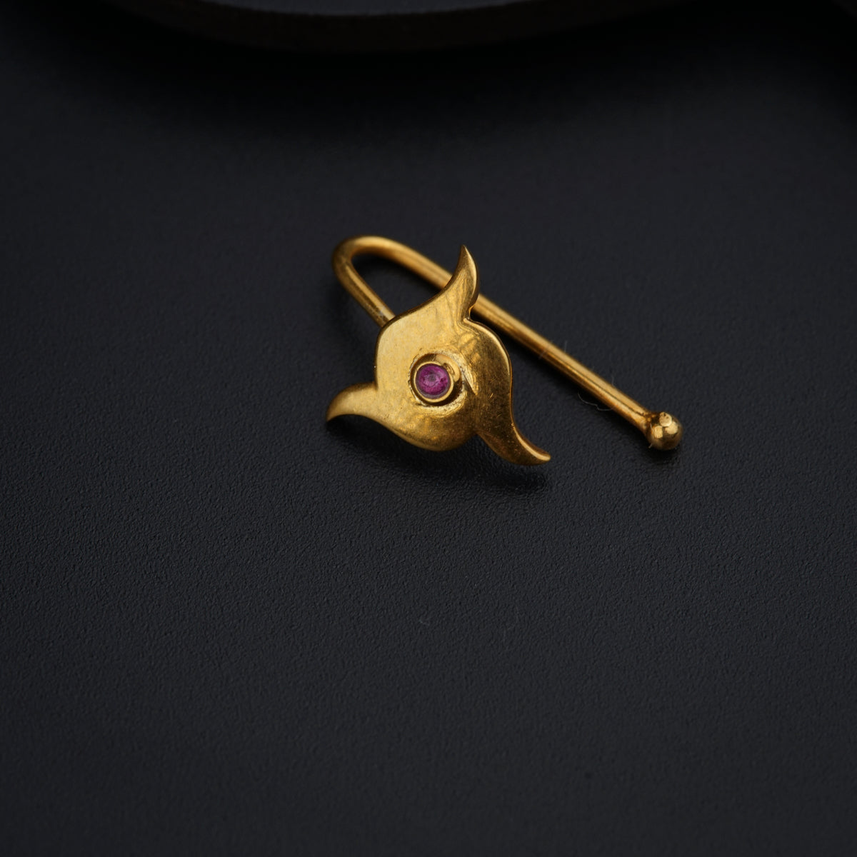 a gold brooch with a pink stone in the center